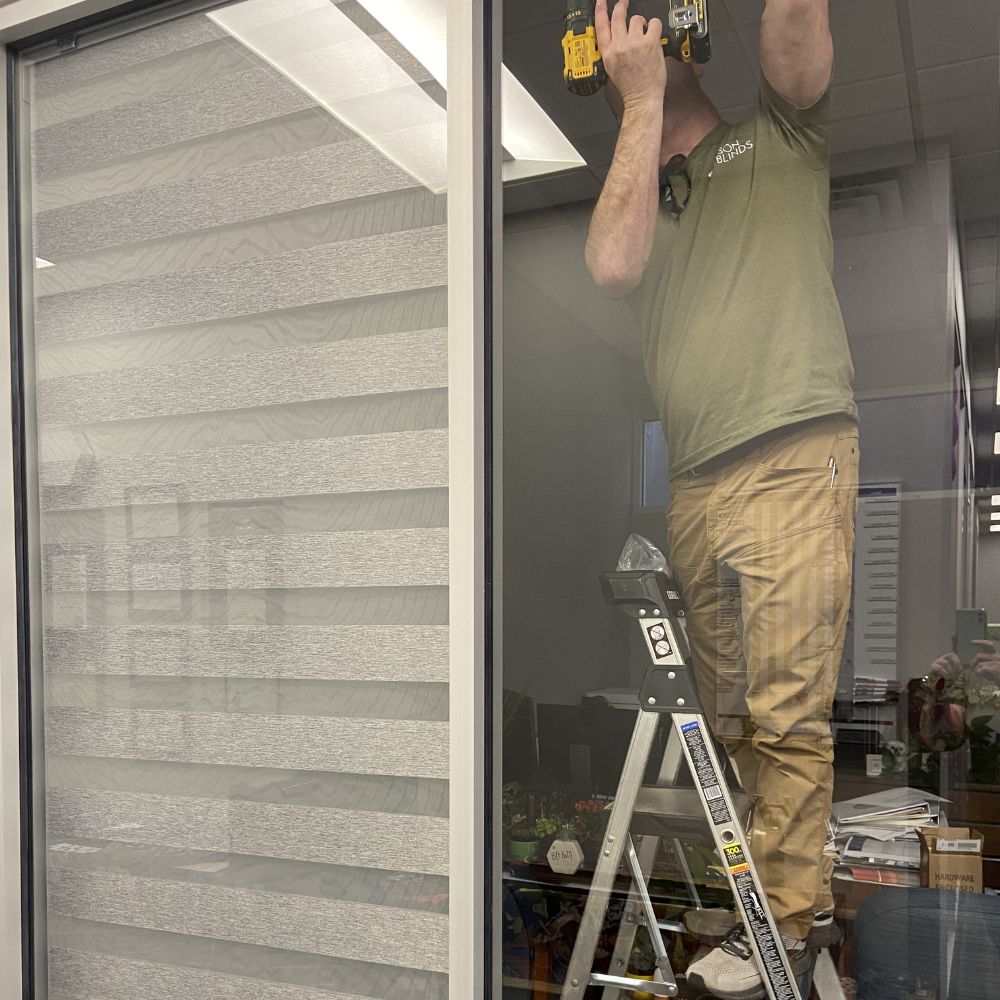 Light gray layered shades installed on office glass wall for privacy control