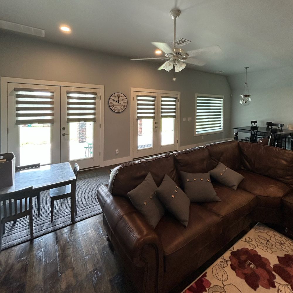 Living room with large windows featuring modern layered shades for light filtering and privacy